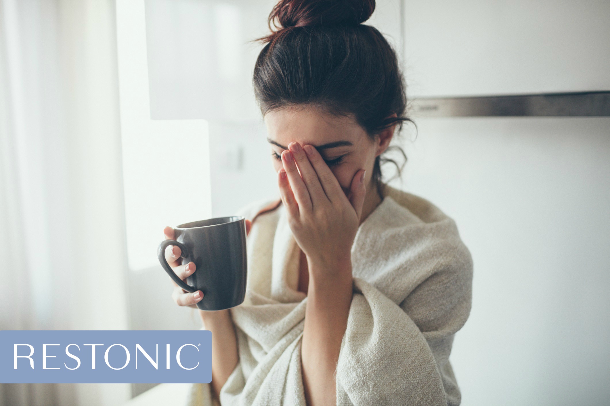 A sleep-deprived woman holding a coffee cup and pondering sleep hacks so she can start her day refreshed.