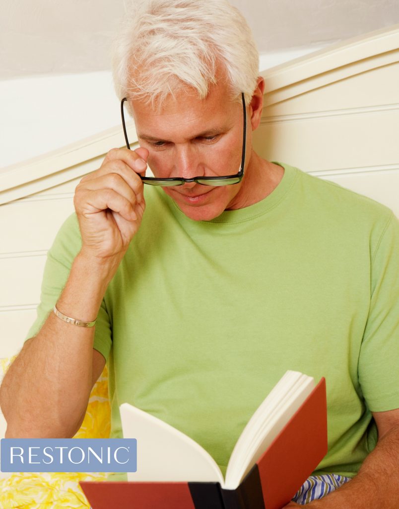 Man reading a book and contemplating How Weighted Blankets Can Help him Sleep better.