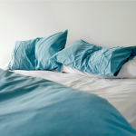 Unmade bed with blue pillows, white sheets, and blue comforter.